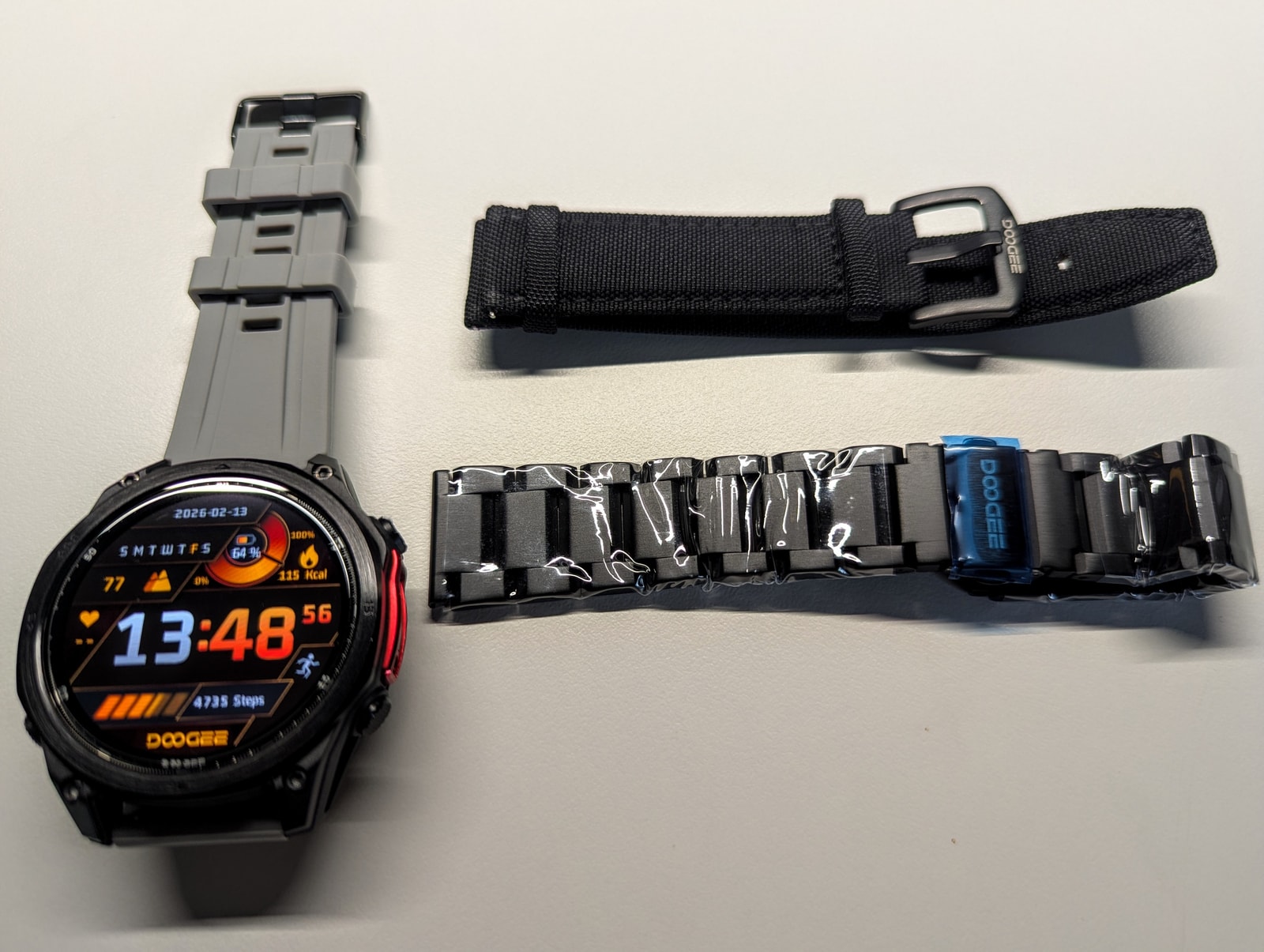 Anywise W1 Pro with the included silicone strap beside the steel and woven nylon spare straps